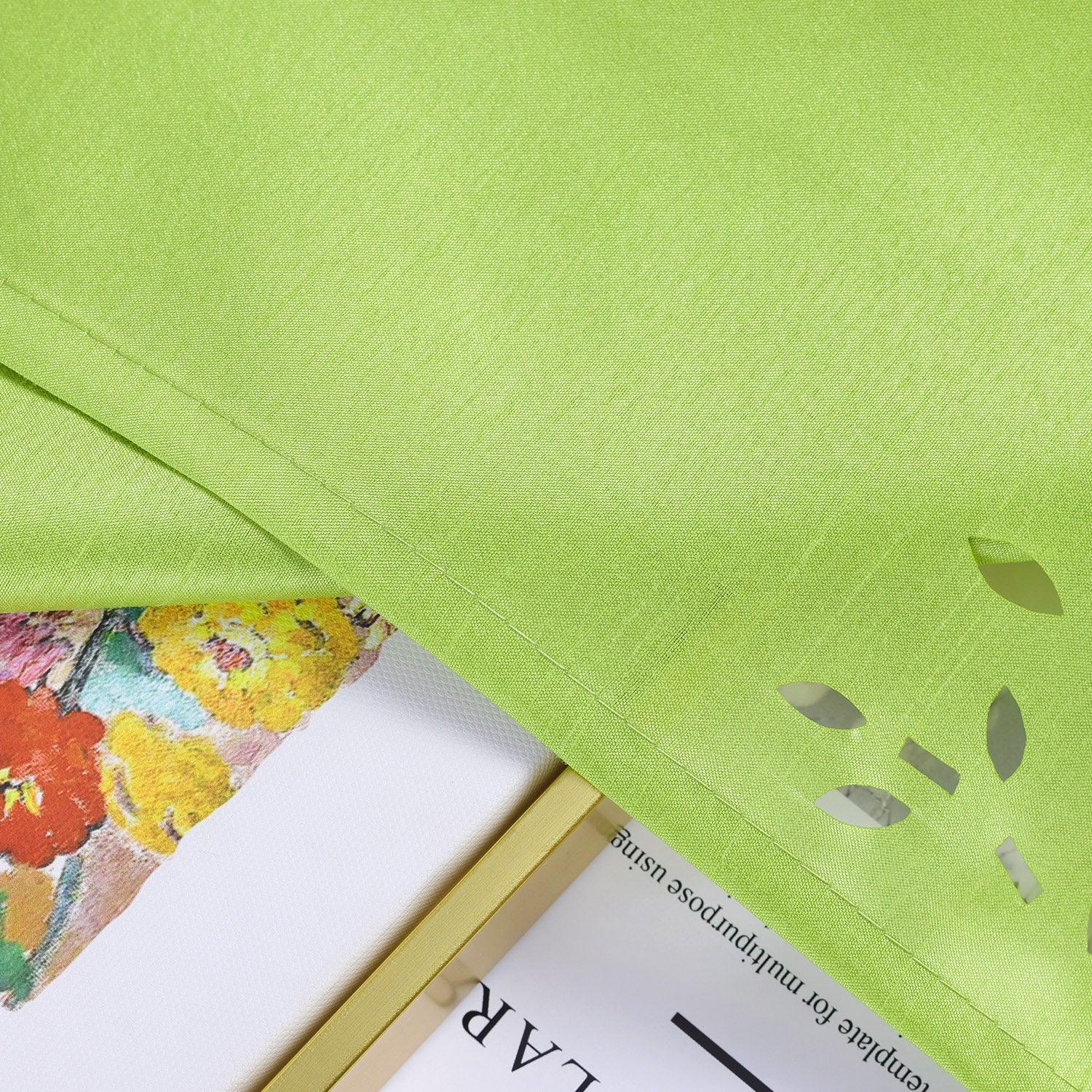Die grüne Scheibengardine liegt flach auf einem Bild, um die feinen Stoffdetails zu präsentieren. Die zarte Webstruktur und das sorgfältig gestaltete Lochmuster heben die hohe Qualität und die feine Handwerkskunst des Materials hervor.