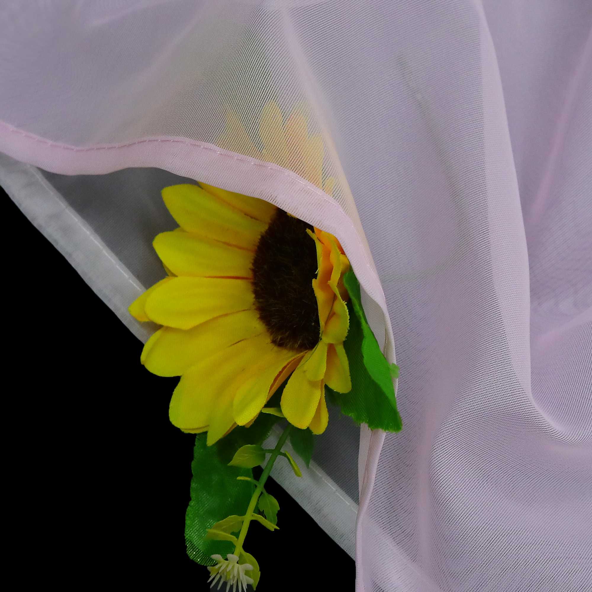 Detail des rosafarbenen Stoffs mit halbdurchsichtiger Konstruktion, darunter sind die Sonnenblumen zu sehen, die Mikro-Mesh-Konstruktion und die rosafarbene Verkleidung.