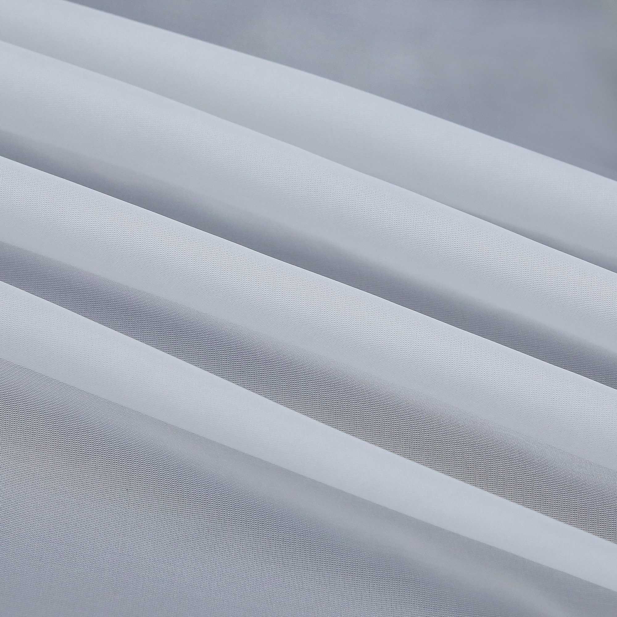 Detail eines grauen, halbtransparenten Gardinenstoffs mit deutlich sichtbarem Saum und sauber gefalteten Kanten. Die feine Struktur des Stoffes lässt das Licht sanft eindringen.