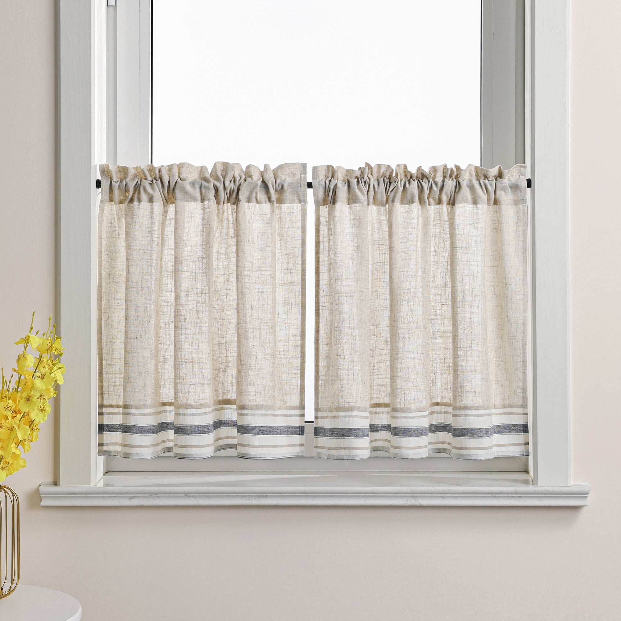 Dies ist eine Gardine im Landhausstil, die am Fenster angebracht ist. Der Hauptstoff ist cremeweiß mit einer Leinenstruktur. Der untere Rand ist mit grauen und weißen Streifen verziert. Diese Scheibengardinen im Landhausstil verleihen Ihrem Raum ein natürliches und schlichtes Ambiente. Sie passen gut zu verschiedenen Einrichtungsstilen wie skandinavischem oder japanischem Design und sorgen für sanftes Licht sowie eine warme, einladende Atmosphäre.
