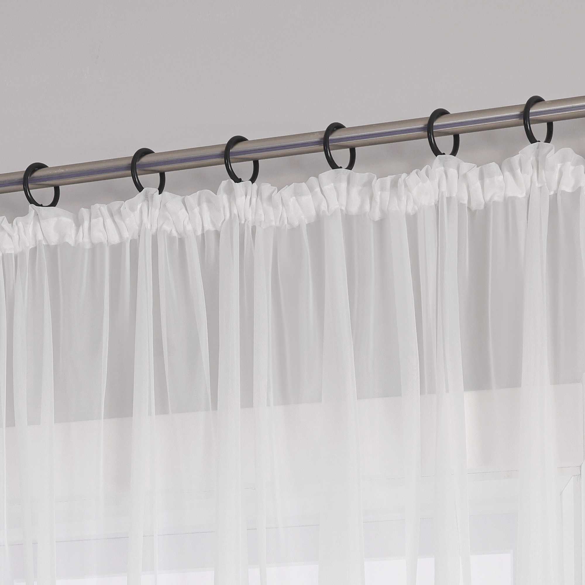 Eine Metallgardinenstange mit schwarzen Ringen, an denen ein weißer Vorhang mit Kräuseln aus transparentem Stoff aufgehängt ist. Der Vorhang hat am oberen Ende ein gerafftes Design.