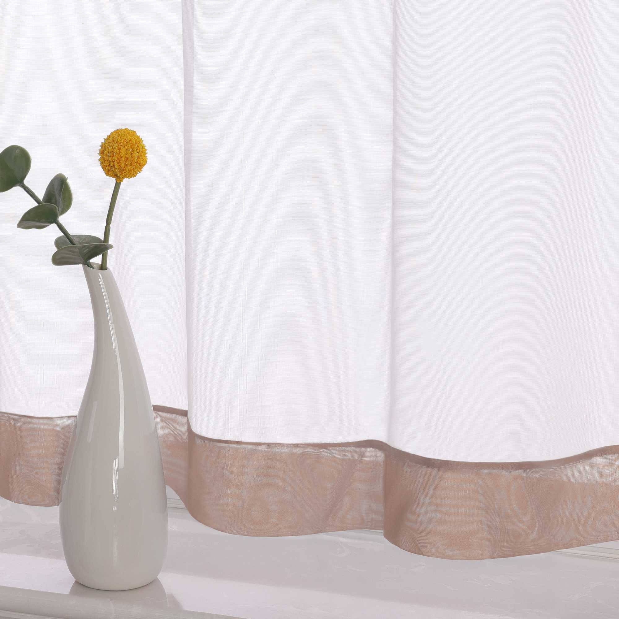 Die Unterkante des Vorhangs wird im Detail gezeigt, mit einem braunem Dekorband als stilvollem Akzent. Ein Vase im Vordergrund ergänzt die Szene und fügt dem Raum eine harmonische, dekorative Note hinzu, die den eleganten Look des Vorhangs unterstreicht.