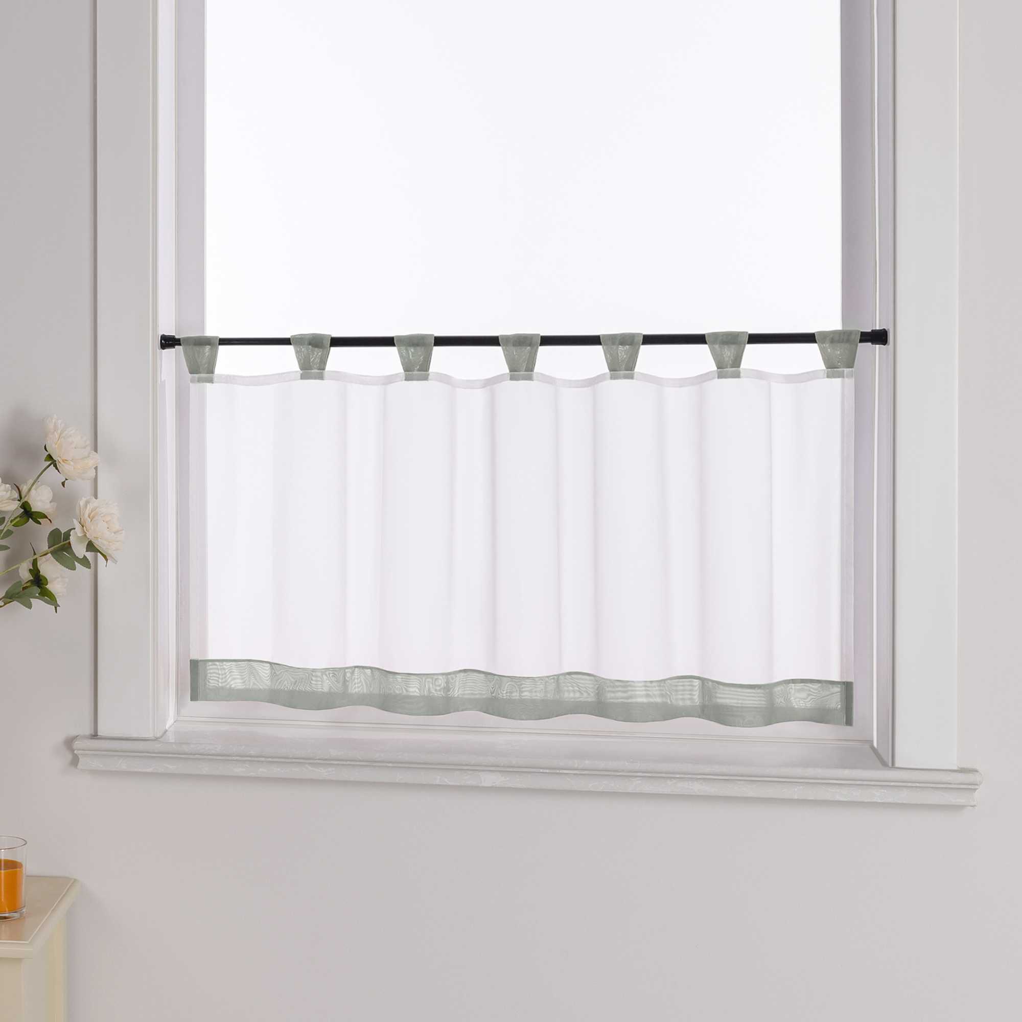 Der weiße Vorhang mit grauem Dekorband wird aus einem seitlichen Winkel fotografiert. Die weiße Wand im Hintergrund betont die Schlichtheit des Designs, während blumige Dekorationen an der Seite dem Raum eine zarte, natürliche Atmosphäre verleihen.