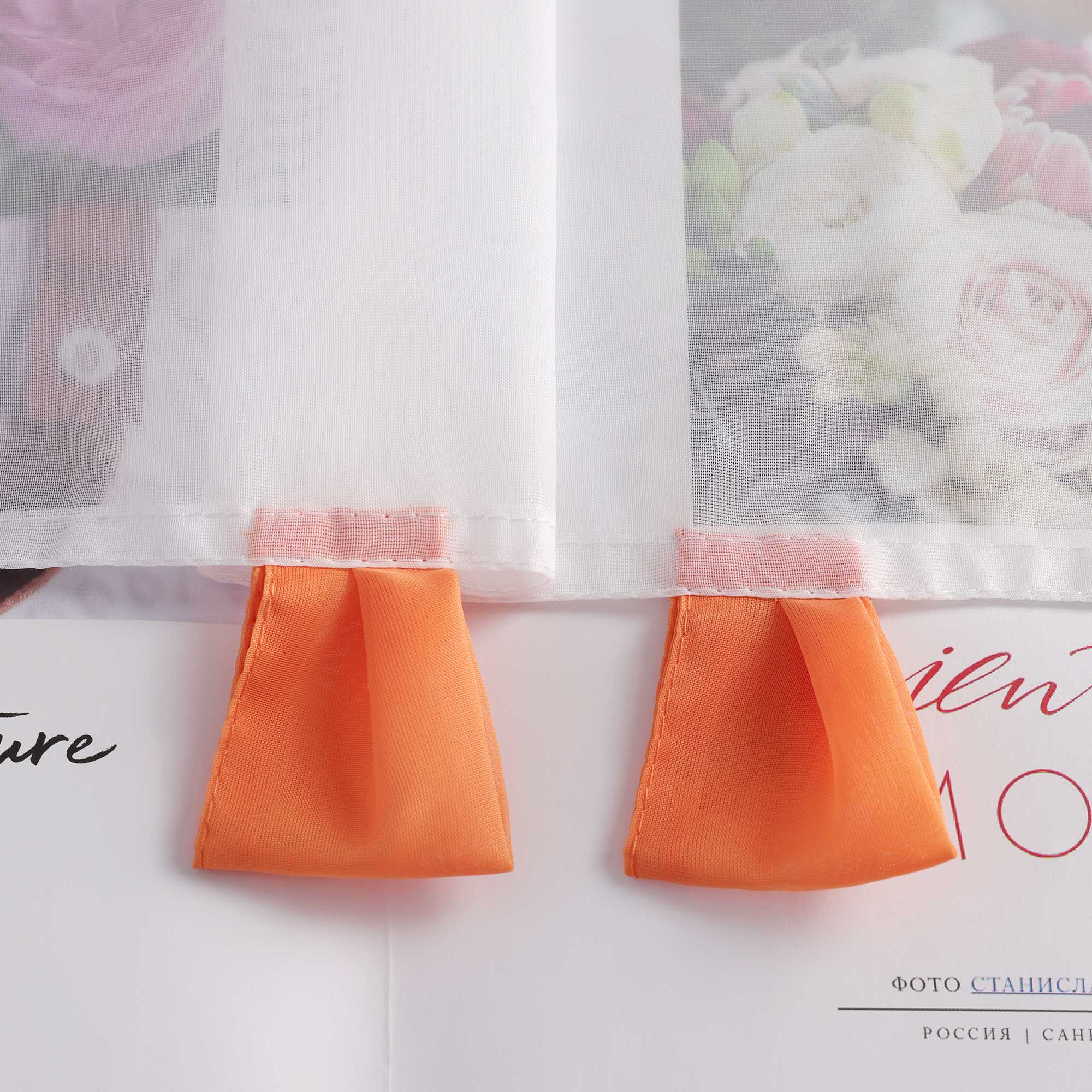 Die orange Schlaufen liegen flach auf dem Tisch, aus transparentem Stoff gefertigt. Die präzise Verarbeitung des Materials sorgt für eine saubere und gleichmäßige Oberfläche, die den eleganten Stil der Schlaufen unterstreicht.