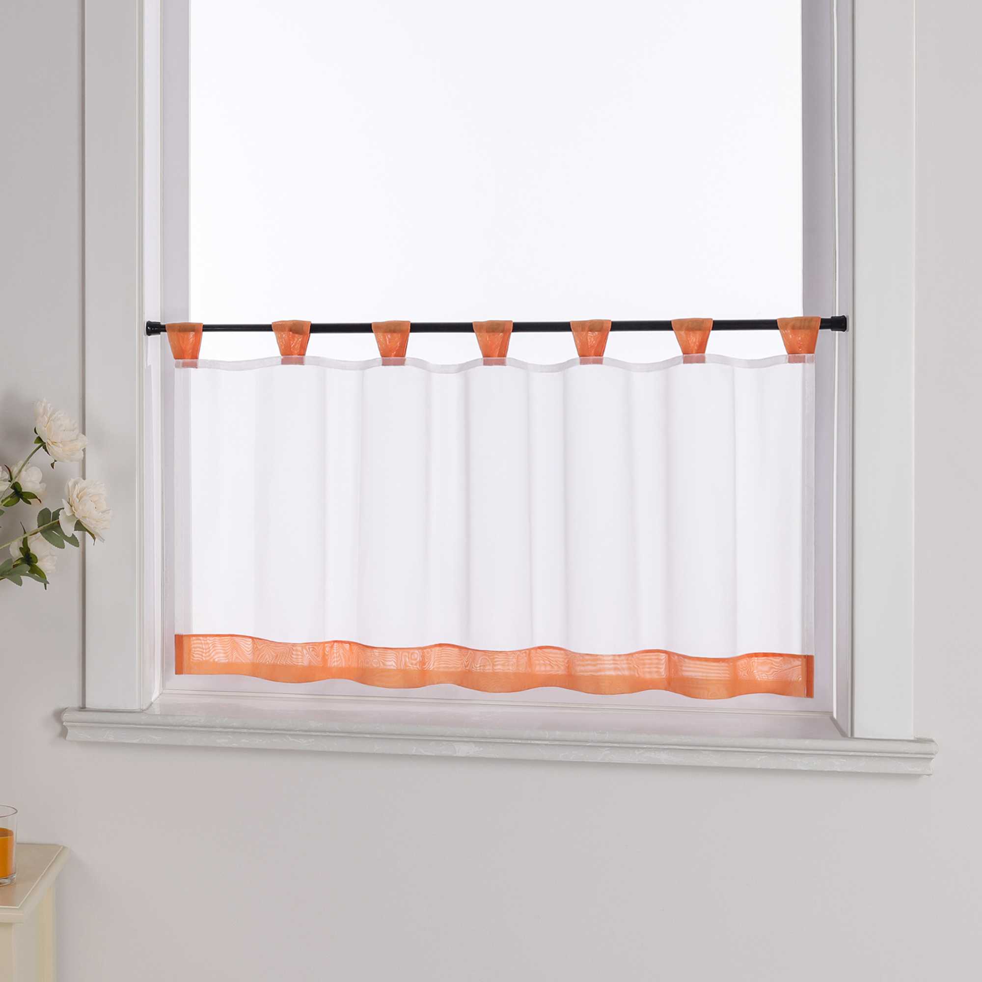 Der weiße Vorhang mit orange Dekorband wird aus einem seitlichen Winkel fotografiert. Die weiße Wand im Hintergrund betont die Schlichtheit des Designs, während blumige Dekorationen an der Seite dem Raum eine zarte, natürliche Atmosphäre verleihen.