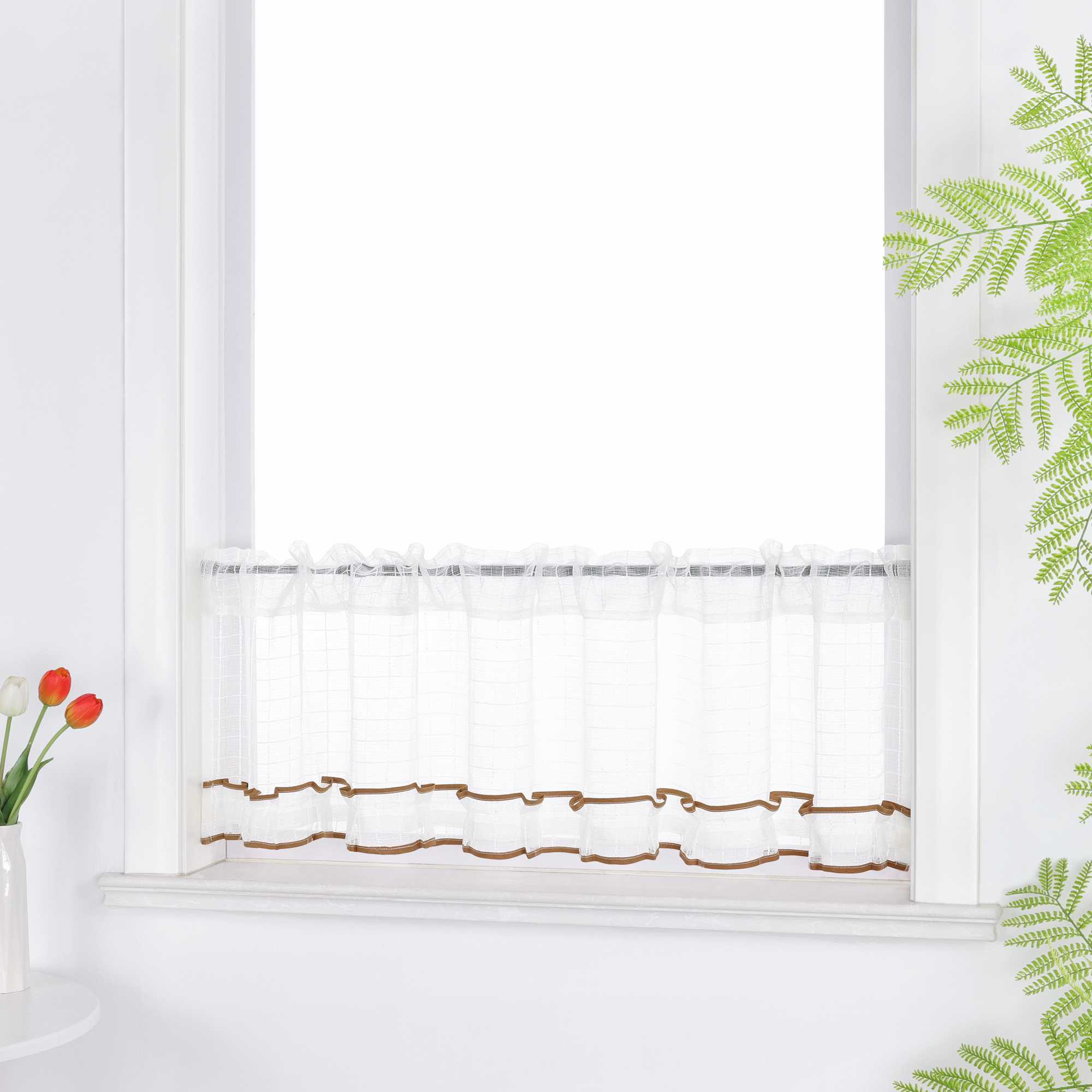 Ein weißer, halbhoher Vorhang aus transparentem Stoff hängt vor dem Fenster. Er zeigt ein feines Karomuster und ist unten mit einer dekorativen, wellenförmigen Borte in Braun verziert. Oben ist der Stoff gerafft und bildet weiche Falten.